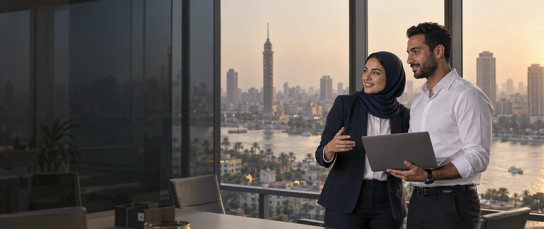 Two colleagues talking in a meeting room overlooking the Cairo skyline